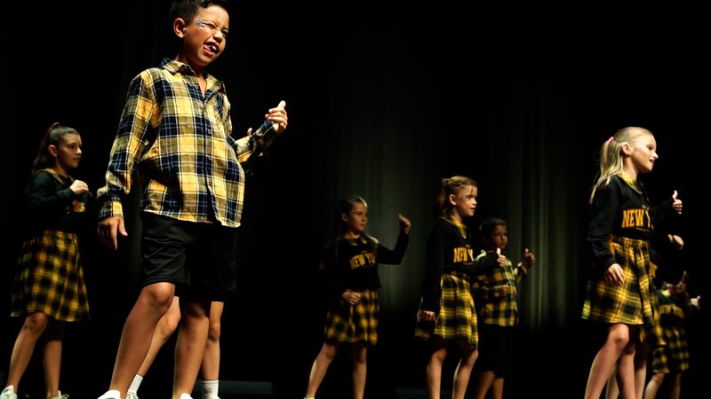Un enfant en chemise à carreaux jaune au premier plan, devant son groupe.