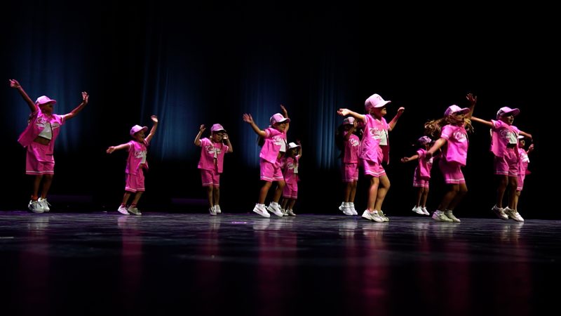 Les enfants en tenues roses et casquettes, alignés sur la scène.