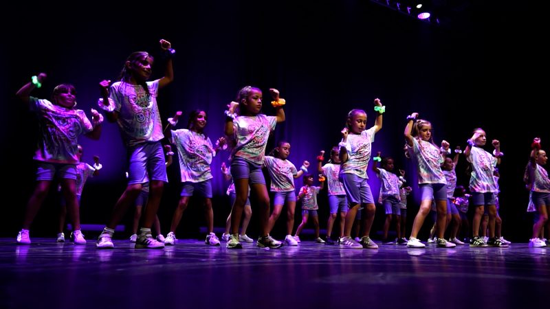 Les enfants en tee-shirts colorés, sous une lumière violette.