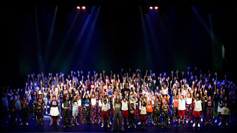Tous les groupes réunis sur scène pour le salut final, bras levés, sous les projecteurs.