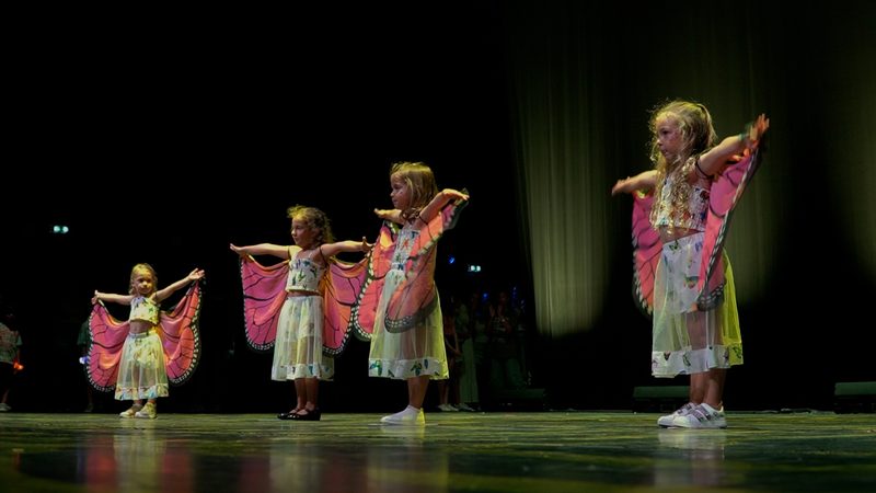 Les plus petits, avec des ailes de papillon roses, en ligne sur la scène.