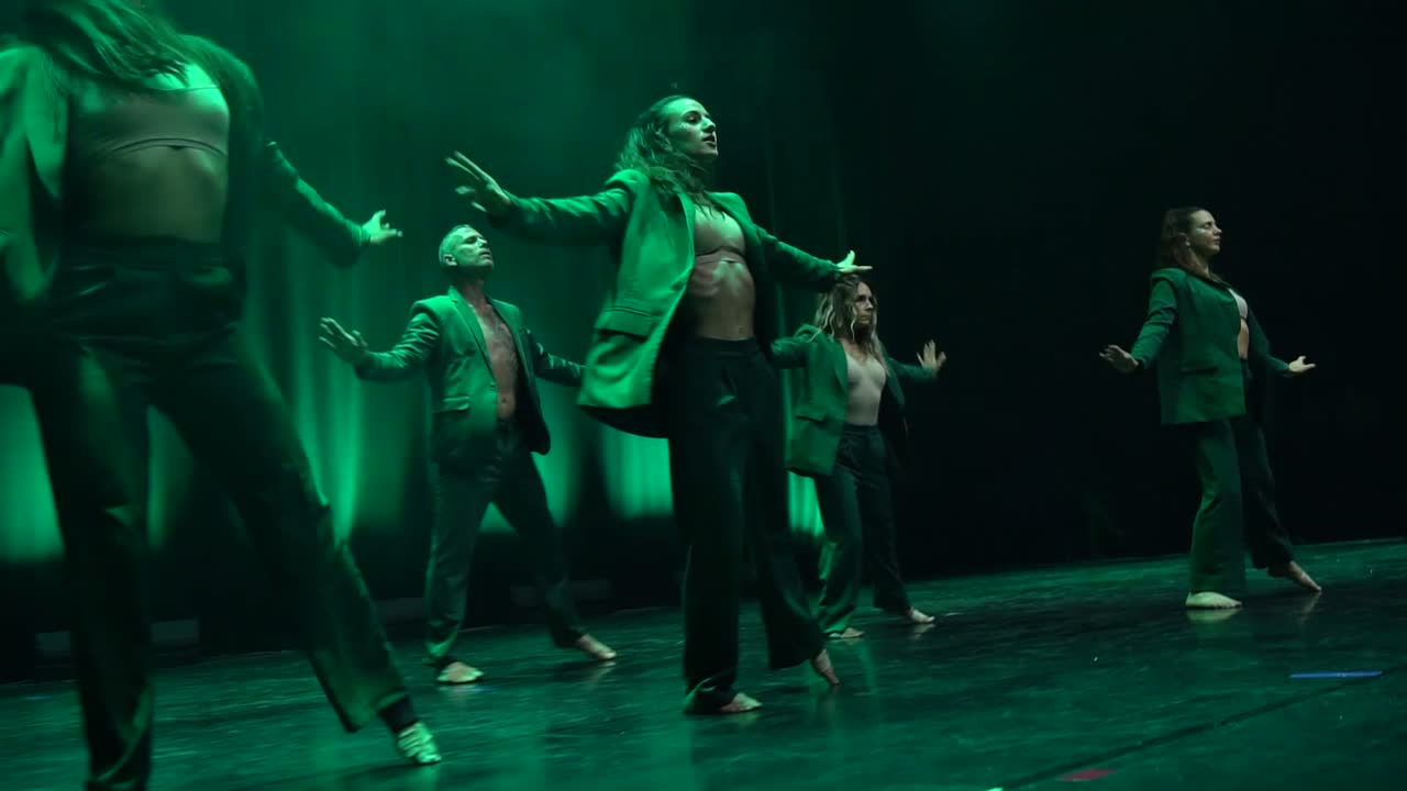 Les danseurs de la pièce « Dualité » en vestes vertes, sur une scène entièrement verte.