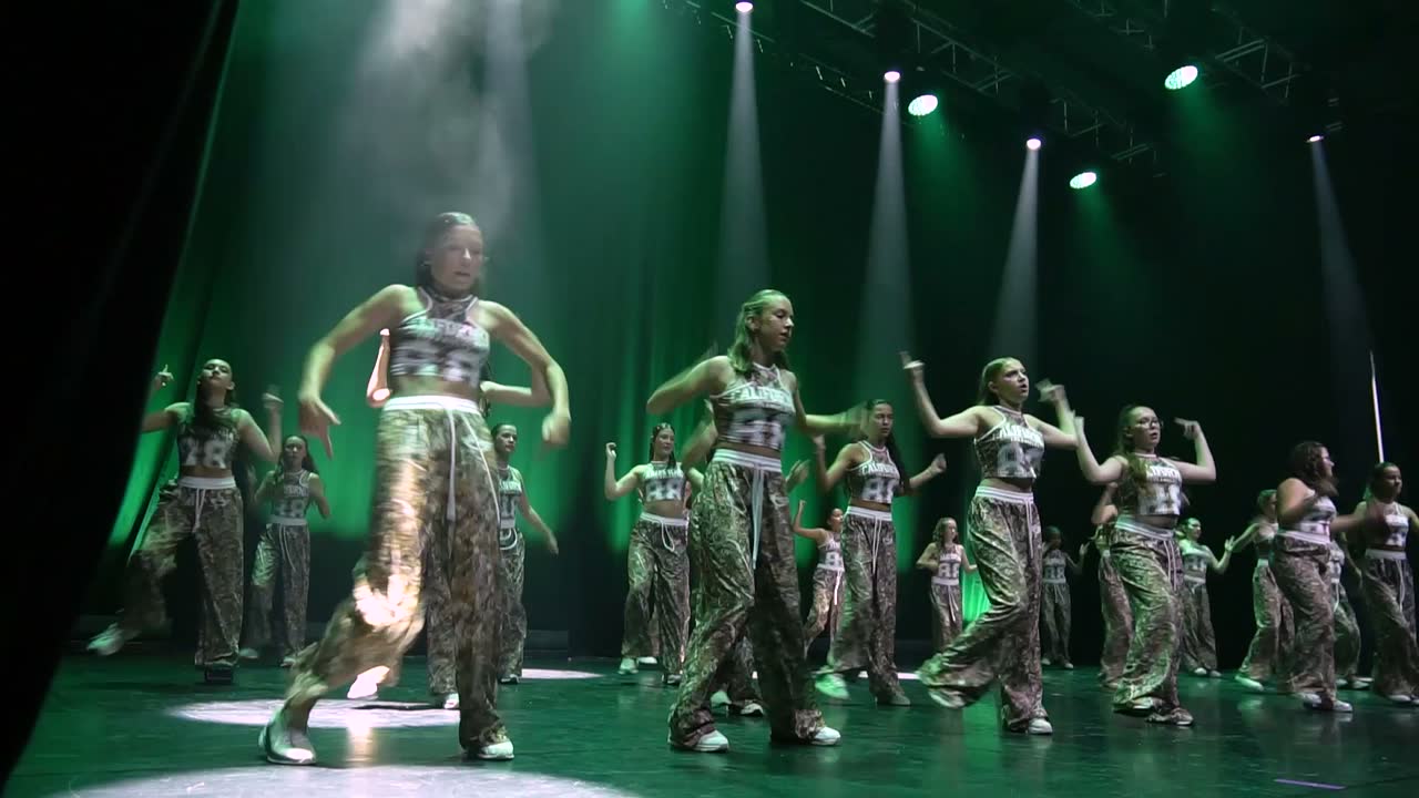 Le groupe hip-hop des 12-14 ans en tenues imprimées, sous des faisceaux verts.