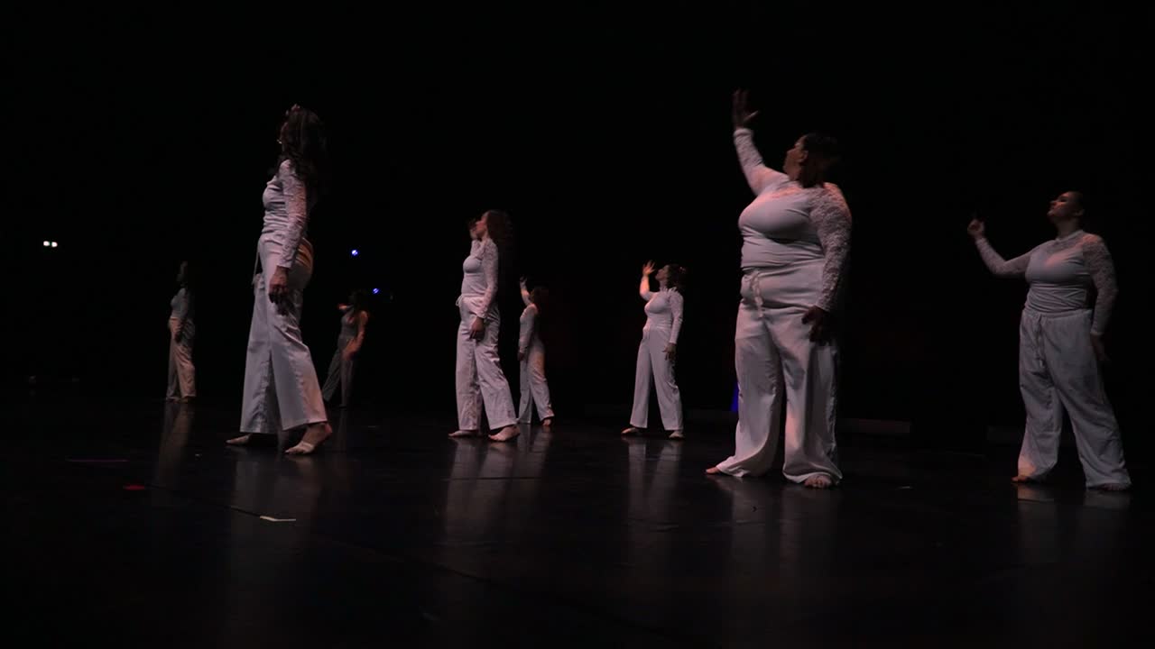 Le groupe lyrical niveau 1 en blanc, bras ouverts, sur le noir du plateau.