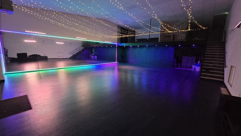 La nouvelle salle : parquet, grand mur de miroirs et rubans de lumière colorée le long des murs.